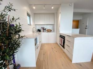 a white kitchen with white cabinets and a wooden floor at HoneyB - 2 bed Apt on the beach in Perth