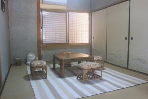 Zimmer mit einem Tisch, 2 Stühlen und einem Tisch in der Unterkunft Annex higashifujita in Moroyose