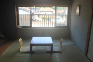 einen Tisch und zwei Stühle in einem Zimmer mit Fenster in der Unterkunft Annex higashifujita in Moroyose