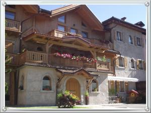 a building with a balcony with flowers on it at AL BORGO ANTICO residenza in Pinzolo