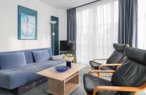ein Wohnzimmer mit einem blauen Sofa und 2 Stühlen in der Unterkunft null Haus Frisia, Whg 404 in Sankt Peter-Ording