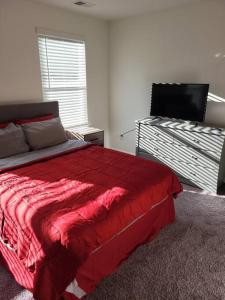 a bedroom with a red bed and a flat screen tv at SC 3745 New Townhouse Ft Jackson & USC in Columbia