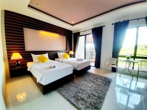 a bedroom with two beds and a large window at Purimas Resortel in Rawai Beach