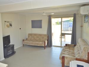 a living room with a couch and a tv at Surf Caster - Kalbarri, WA in Kalbarri