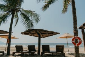 un grupo de sillas y sombrillas en la playa en Las Palmas Luxury Villas en Zihuatanejo