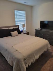 a bedroom with a bed with a dresser and a television at SC 3755 New 2 bedroom Townhouse Ft Jackson & USC in Columbia