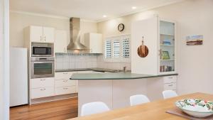 a kitchen with white appliances and a wooden table at 20 Mackay St Dicky Beach QLD in Caloundra