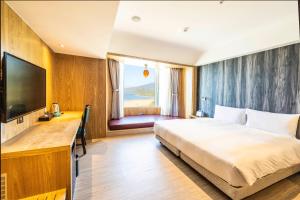 a bedroom with a bed and a desk and a television at Kenting Long Beach Hotel in Checheng