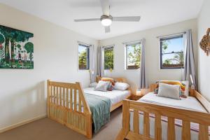 two beds in a room with two windows at Little Whale House in Mudjimba