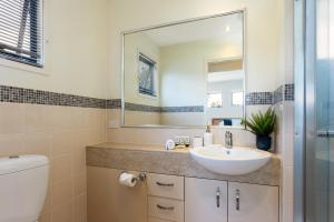 a bathroom with a sink and a toilet and a mirror at Little Whale House in Mudjimba