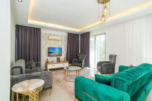 ein Wohnzimmer mit einem grünen Sofa und Stühlen in der Unterkunft Hisarönü'de 4 Yatak Odalı Villa-Villa Bahama in Fethiye