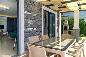 eine Terrasse mit einem Glastisch und Stühlen in der Unterkunft Hisarönü'de 4 Yatak Odalı Villa-Villa Bahama in Fethiye