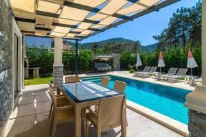 eine Terrasse mit Tisch und Stühlen neben einem Swimmingpool in der Unterkunft Hisarönü'de 4 Yatak Odalı Villa-Villa Bahama in Fethiye