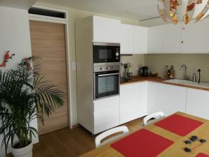 a kitchen with white cabinets and a table and a microwave at Balcons du Royans.Logement entier Piscine in Saint-Jean-en-Royans