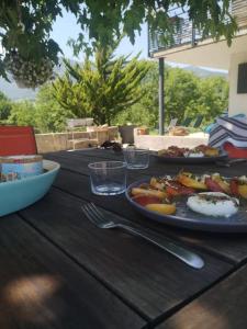 una mesa de madera con dos platos de comida. en Balcons du Royans.Logement entier Piscine, en Saint-Jean-en-Royans