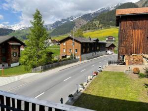 an empty road in a village with houses and mountains at Via Alpsu 143 in Sedrun