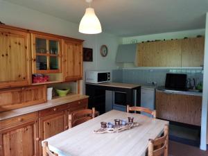 una cocina con armarios de madera y una mesa con sillas. en Appartement Mont-Dore, 2 pièces, 4 personnes - FR-1-415-92, en Le Mont-Dore