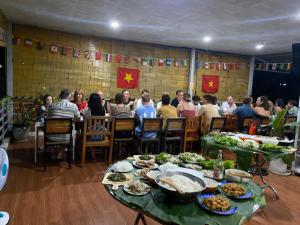 un grupo de personas sentadas en una mesa con comida en Orchid Guesthouse en Phu Quoc