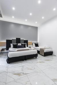 2 letti in una camera con pareti bianche e pavimenti in marmo di Hotel Sant'Angelo Palace a Napoli
