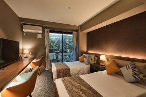 a hotel room with two beds and a flat screen tv at Sekia Wagaya Hotel in Karahashi Rashomon