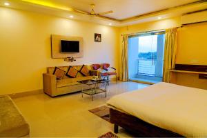 a bedroom with a bed and a couch and a tv at FabHotel Kanchan Plaza in Bhubaneshwar