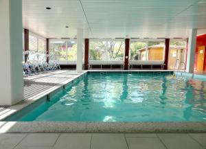 a swimming pool in a building with blue water at Vitalhotel König am Park in Bad Mergentheim