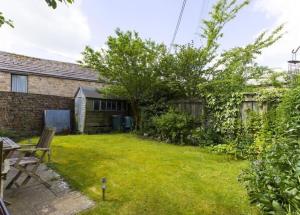 a backyard of a house with a grass yard at Cringley Cottage in Askrigg