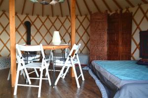 two chairs and a table in a yurt with a bed at Dzika Jurta na Łebkach in Łebki