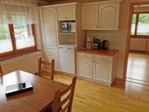 a kitchen with white cabinets and a wooden table at Haus Post in Todtnau