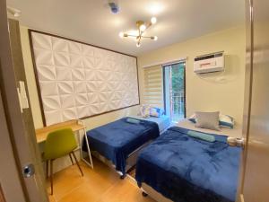 Cette chambre comprend deux lits, un bureau et une fenêtre. dans l'établissement Resort-type 2 bedroom Unit by OneOasisHaven, à Cagayán de Oro