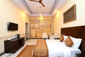 ein Hotelzimmer mit einem Bett und einem Fernseher in der Unterkunft Aaram Baagh Maheshwar in Maheshwar