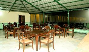 une salle à manger avec des tables et des chaises en bois dans l'établissement Aaram Baagh Maheshwar, à Maheshwar