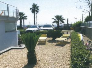 a patio with benches and palm trees and a parking lot at Casa Airone in SantʼAlessio Siculo