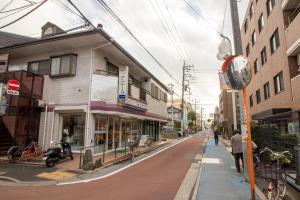 uma rua com edifícios e pessoas andando no passeio em ミニマリズムホテル葛飾 em Tóquio