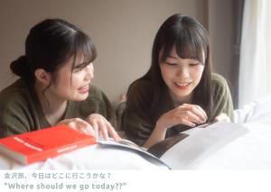 twee vrouwen die een boek lezen terwijl ze aan tafel zitten bij LINNAS Kanazawa in Kanazawa