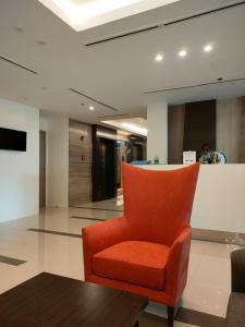 an orange chair in a lobby with a table at 2BR Pioneer Woodlands SM LIGHT by AwayHome Rentals in Manila