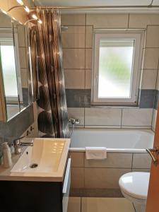 a bathroom with a sink and a tub and a window at Haus Post in Todtnau