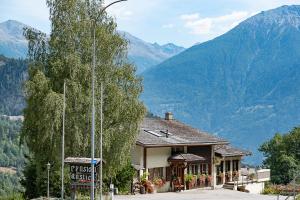 a sign in front of a building with mountains in the background at B&B Pension Rustica in Inden