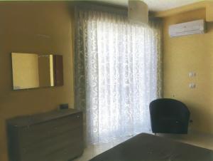 a room with a window with a chair and a television at Casa Airone in SantʼAlessio Siculo +3 photos
