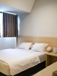 sypialnia z łóżkiem z białą pościelą i oknem w obiekcie Mendjangan Residence w Dżakarcie