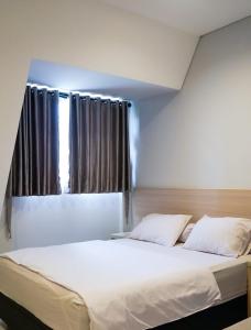 sypialnia z dużym białym łóżkiem i oknem w obiekcie Mendjangan Residence w Dżakarcie