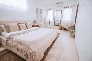 um quarto branco com uma cama grande e um espelho em Hotel Sages em Canggu