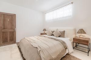 a white bedroom with a bed and a window at Hotel Sages in Canggu