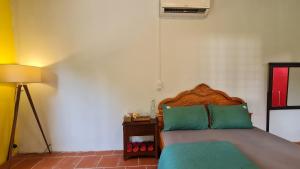 a bedroom with a bed with green pillows and a lamp at Maison du Pays de Bến Tre in Ben Tre