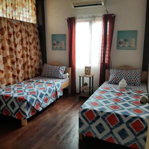 a bedroom with two beds and a window at Ella's Beach House in Tuble