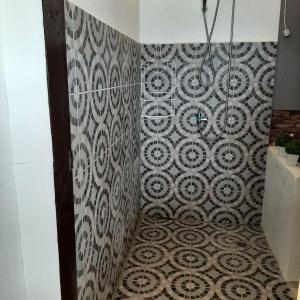 a bathroom with a shower with a patterned wall at Ella's Beach House in Tuble
