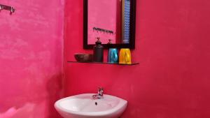 a pink bathroom with a sink and a mirror at Maison du Pays de Bến Tre in Ben Tre