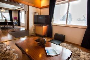 a living room with a table and a tv at RUSUTSU HOLIDAY CHALET / Vacation STAY 3822 in Makkari