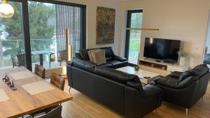 sala de estar con sofá de cuero negro y mesa en Lipno A1, en Lipno nad Vltavou