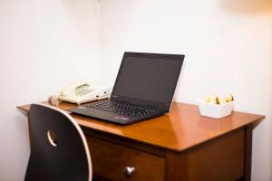 a laptop computer sitting on a desk with a phone at Perth City Living 105 in Perth